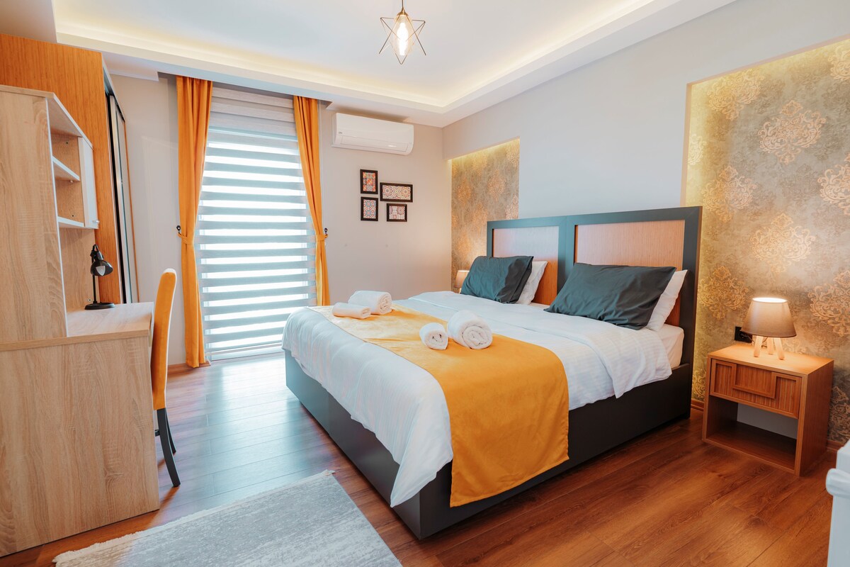 Un dormitorio moderno con cama, mesita de noche y escritorio con silla.