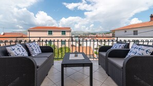 A balcony with wicker furniture and a table, overlooking a town with red-roofed buildings and a clear sky. - IGNACIJA 1 - Apartment 3+1 people, sea view terrace (Okrug Gornji)