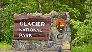 A sign for Glacier National Park with a National Park Service emblem.