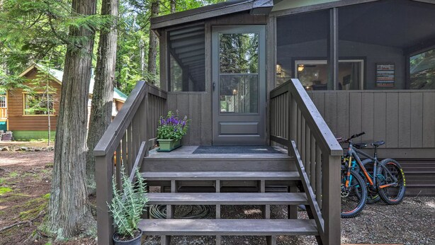 A wooden cabin with a porch, steps, and a door. There are bicycles parked outside.