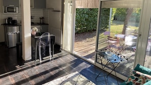 A modern kitchen with a built-in microwave, refrigerator, and a dining area with a glass door leading to a patio. - Charming gîte in a green setting with swimming pool South Ardèche (Berrias-et-Casteljau)