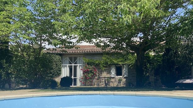 A swimming pool with a stone house in the background. - Charming gîte in a green setting with swimming pool South Ardèche (Berrias-et-Casteljau)