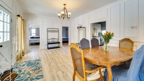 Un'ampia sala da pranzo con un tavolo e sedie in legno, un lampadario e vista sulla cucina.