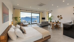 Habitació d'hotel moderna amb un llit gran, zona de menjador, sofà i cuina.