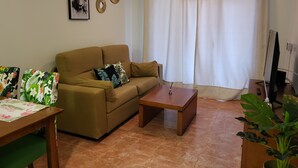 Ein Wohnzimmer mit einer Couch, einem Couchtisch und einem Flachbildfernseher.