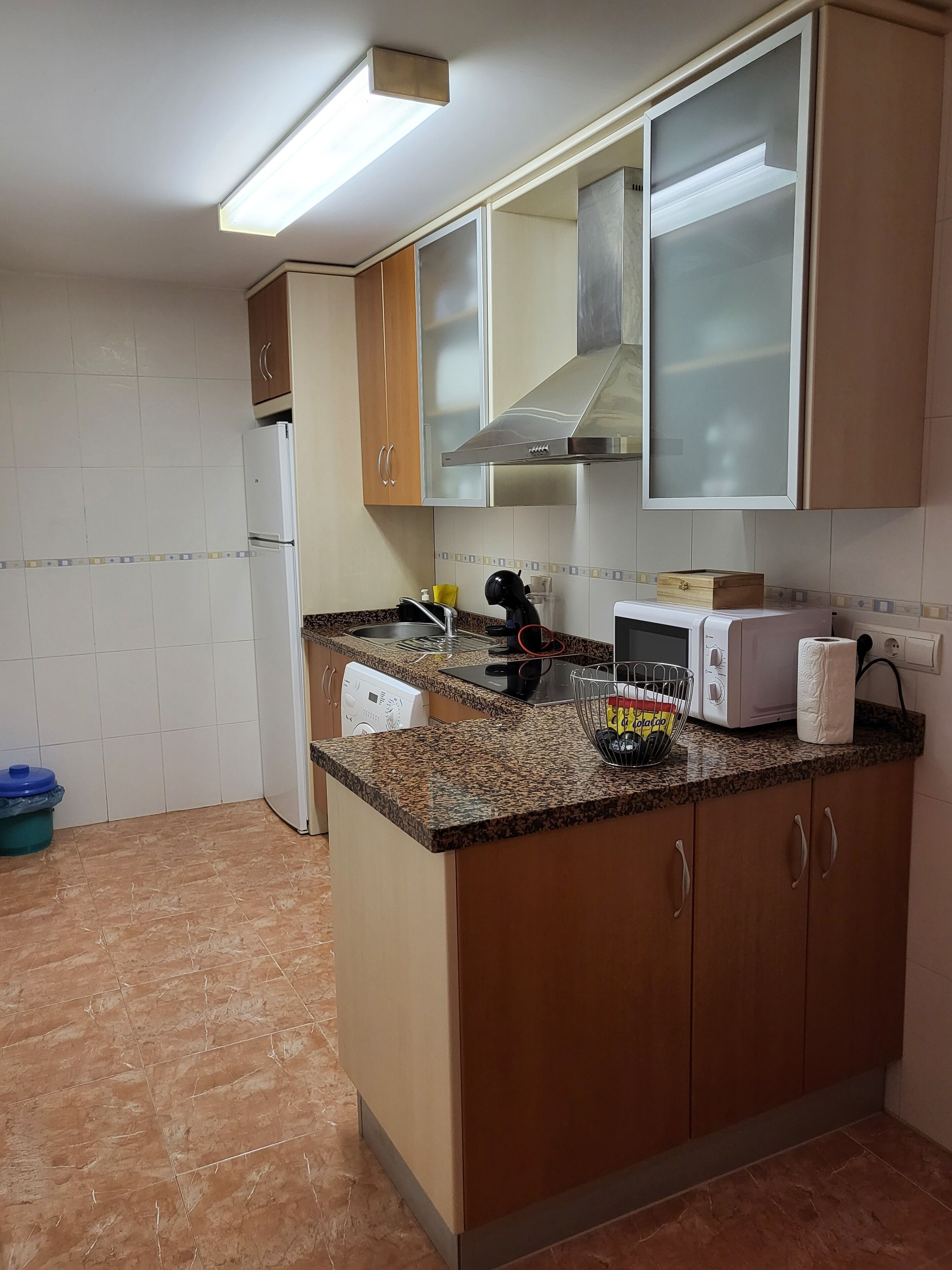 Una cocina con encimera de granito, microondas, tostadora y lavavajillas.