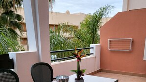 Eine Terrasse im Freien mit Tisch, Stühlen, einem Blumentopf und einer Brüstung.