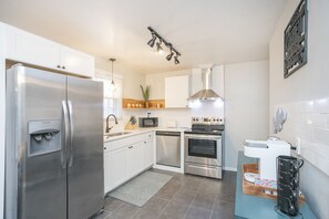 A modern kitchen with stainless steel appliances, white cabinets, and a built-in microwave.