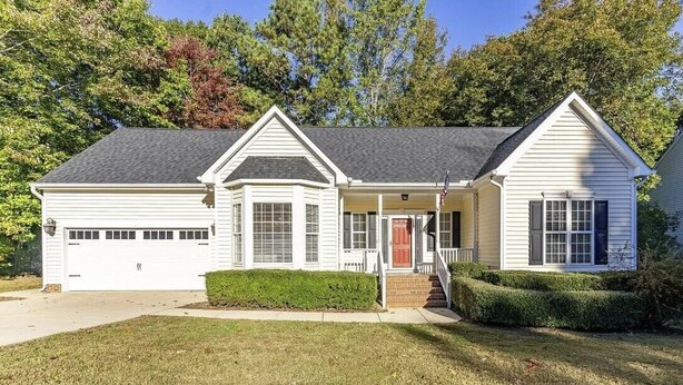 A single-story house with a front porch, a garage, and a well-maintained lawn. - Remodeled ranch style home with Firepit conveniently located (Raleigh)