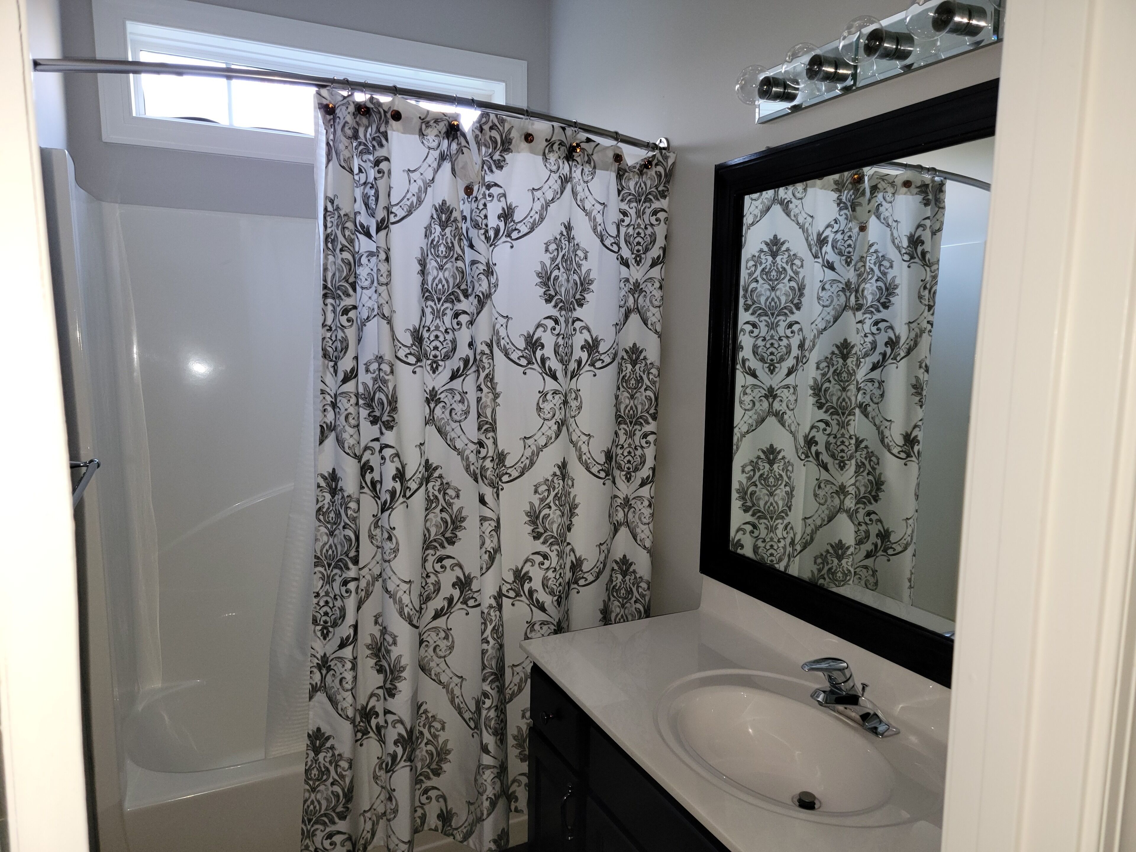 A bathroom with a shower curtain, a sink, and a mirror.