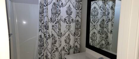 A bathroom with a shower curtain, a sink, and a mirror.
