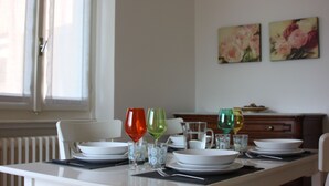 Et spisebord dækket med tallerkener, glas og bestik. To billeder hænger på væggen bag bordet.