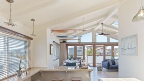 A modern kitchen with a bar area, large windows, and a dining area with a sofa. - 3809 Sea Foam Oasis - One Block to Miles of Beach (Monterey)