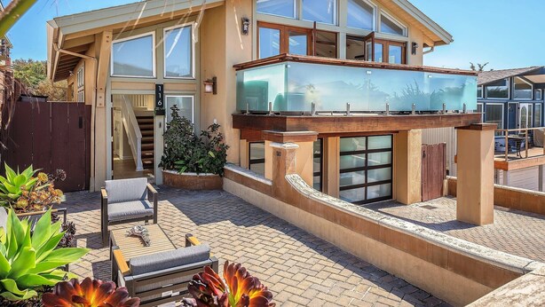 A modern two-story house with a balcony, outdoor seating area, and a staircase leading to the upper level. - 3809 Sea Foam Oasis - One Block to Miles of Beach (Monterey)