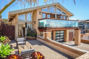 A modern two-story house with a balcony, outdoor seating area, and a staircase leading to the upper level. - 3809 Sea Foam Oasis - One Block to Miles of Beach (Monterey)