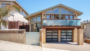 A modern two-story house with a garage, large windows, and a balcony. - 3809 Sea Foam Oasis - One Block to Miles of Beach (Monterey)