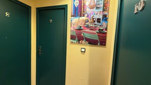 A hallway with two doors, one marked with the number 8 and the other with 10. A colorful painting of a dining scene is displayed on the wall between the doors. - Hotel Le Beausejour (Marseille)