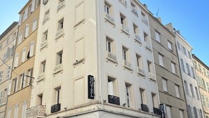 A multi-story hotel with a classic architectural style, featuring balconies with intricate railings, multiple windows, and a prominent 'HOTEL' sign on the facade. - Hotel Le Beausejour (Marseille)