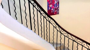 A staircase with a wooden handrail and black metal balusters, leading to a landing with a poster on the wall. - Hotel Le Beausejour (Marseille)