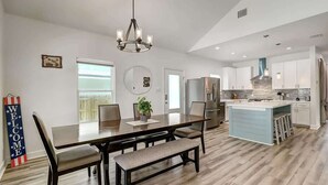 Une cuisine moderne dotée d’un îlot central, d’un coin repas avec une banquette et d’un lustre.