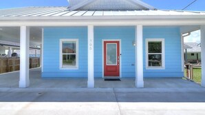 Une maison de plain-pied avec une porte rouge, portant le numéro 705, et un porche couvert.