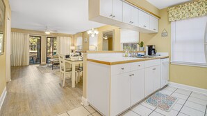 A kitchen with white cabinets, a wooden countertop, and a dining area with a table and chairs. - PP 200-2 Golfers Paradise in Pawleys Plantation (Pawleys Island)