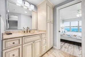 A bathroom with a large mirror, a sink with a faucet, and a vanity with drawers. - Emerald Towers 1007 * Beach Chair Set Included (Fort Walton Beach)