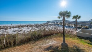 A beach with a wooden walkway, palm trees, and a clear blue sky. - Emerald Towers 1007 * Beach Chair Set Included * Salt Water Vacations (Fort Walton Beach)