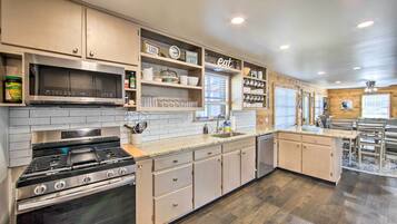 A modern kitchen with stainless steel appliances, wooden cabinets, and a built-in microwave.