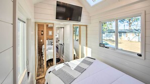 Un dormitorio con cama, televisor montado en el techo y ventana con vista al exterior.