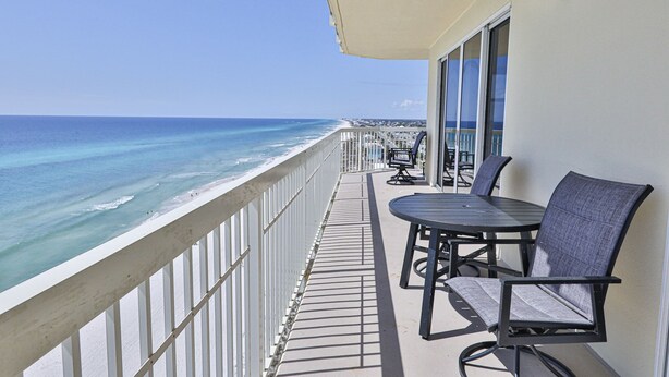 A balcony with a view of the ocean, a table with chairs, and a railing. - Gulf front end unit w/ wraparound balcony, Sunset ocean views, 3BR 3BA! (Panama City Beach)