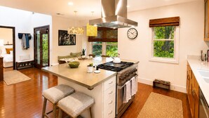 A modern kitchen with a central island, stainless steel appliances, and a view of greenery outside. - Casa Clarkson
Mid-century modern getaway in West LA. Close to beach & shops. (Los Angeles)