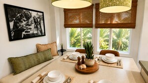 A dining area with a table set for four, a sofa, a framed picture on the wall, and a view of palm trees through the window. - Casa Clarkson
Mid-century modern getaway in West LA. Close to beach & shops. (Los Angeles)