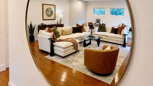 A modern living room with a round mirror, white sofas, a coffee table, and a brown armchair. - Casa Clarkson
Mid-century modern getaway in West LA. Close to beach & shops. (Los Angeles)