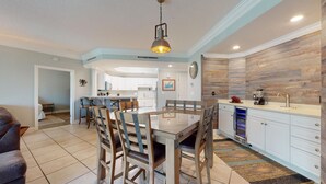 A modern kitchen with a central island, white cabinetry, and a wooden backsplash.