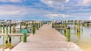 A wooden pier leading to a marina with boats docked, and a sign prohibiting shopping or luggage carts in the marina area.