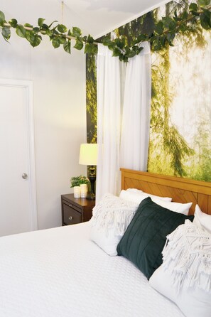 A bedroom with a bed, a nightstand, a lamp, and a wall with a nature-themed mural. - 3BR Cottage with Goats, Covered Patio & Grill, Near Fishhawk (Lithia)