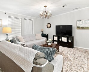 A living room with a sofa, coffee table, TV, and decorative items.