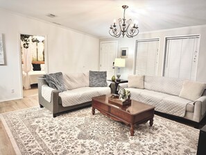 A living room with two sofas, a coffee table, a chandelier, and a patterned rug. - 3BR Cottage with Goats, Covered Patio & Grill, Near Fishhawk (Lithia)