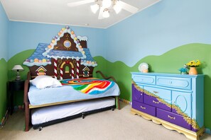 A bedroom with a bed, a dresser, a nightstand, and a ceiling fan.