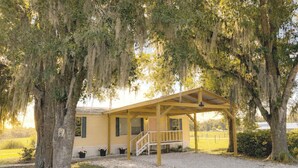 A single-story house with a porch, surrounded by trees with hanging moss. - Relaxing Cottage Near Fishhawk (Lithia)