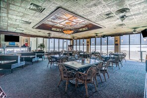 A spacious dining area with high ceilings, large windows, and a central chandelier. - Oceanfront Sands Beach Club #724 | Shore Dr Myrtle Beach | Renovated | 2 BR (Myrtle Beach)