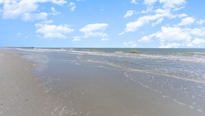 Een strand met heldere lucht en golven.