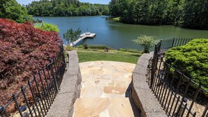 Un escalier en pierre mène à une jetée au bord d’un lac, lui-même entouré d’une végétation luxuriante.