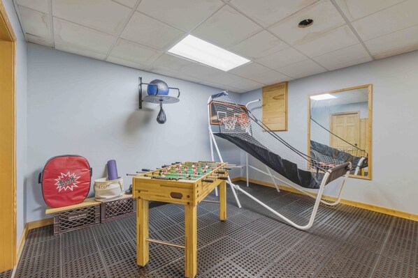 Une pièce avec un baby-foot, un sac rouge, un tapis de yoga et un hamac.