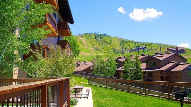 Zona residencial con casas, una terraza de madera y vistas a un valle verde.