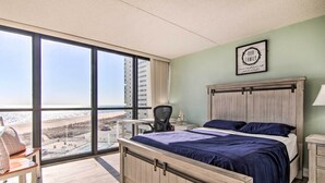 Una habitación de hotel con un ventanal grande, una cama, un escritorio y una silla.