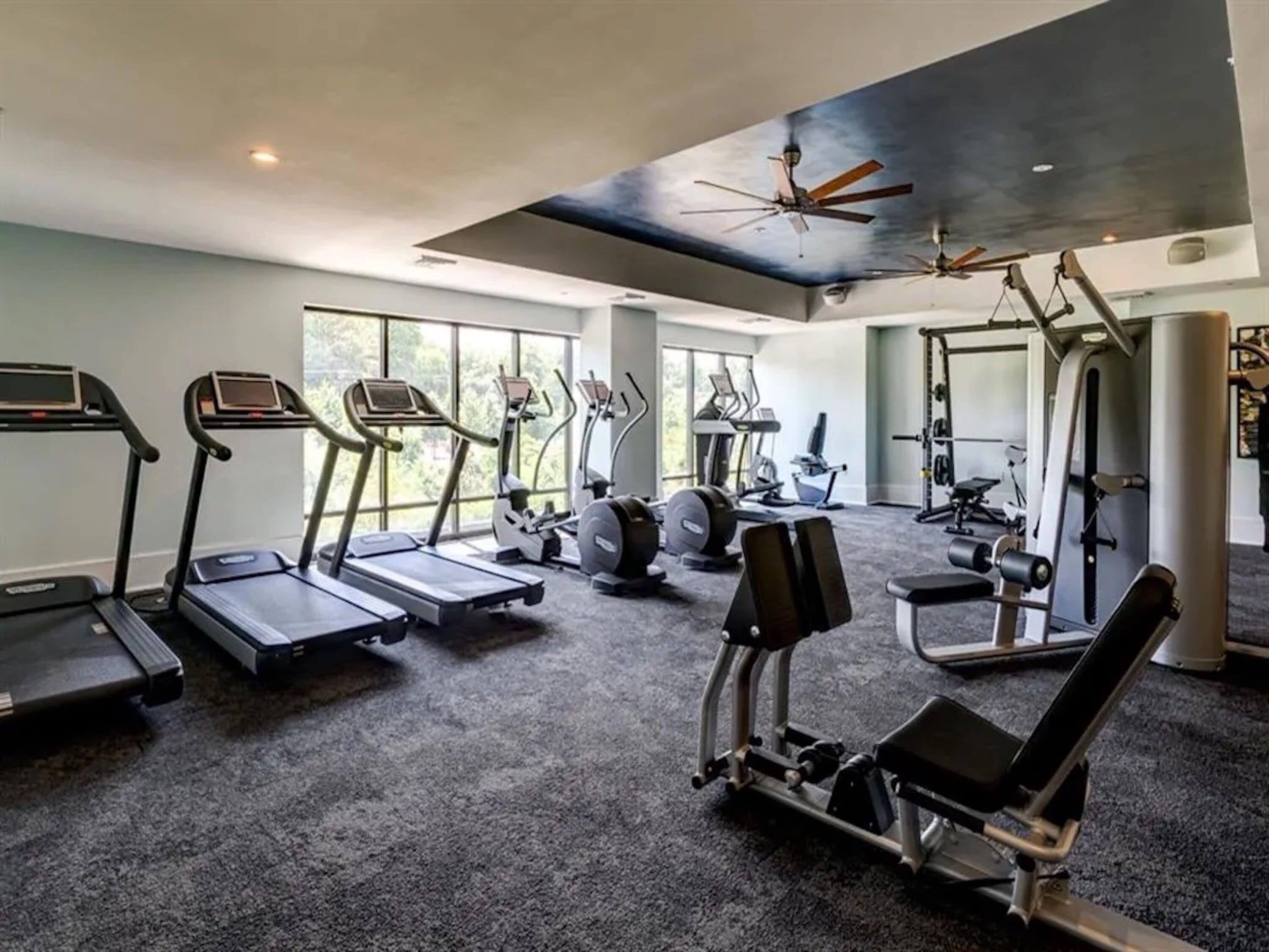 A gym with treadmills, elliptical machines, and weightlifting equipment.