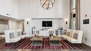 A spacious living room with a large fireplace, white sofas, and a modern chandelier. - Kasa Dilworth Charlotte (Charlotte)