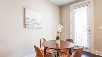 A dining area with a round table, six chairs, and a vase with white flowers.